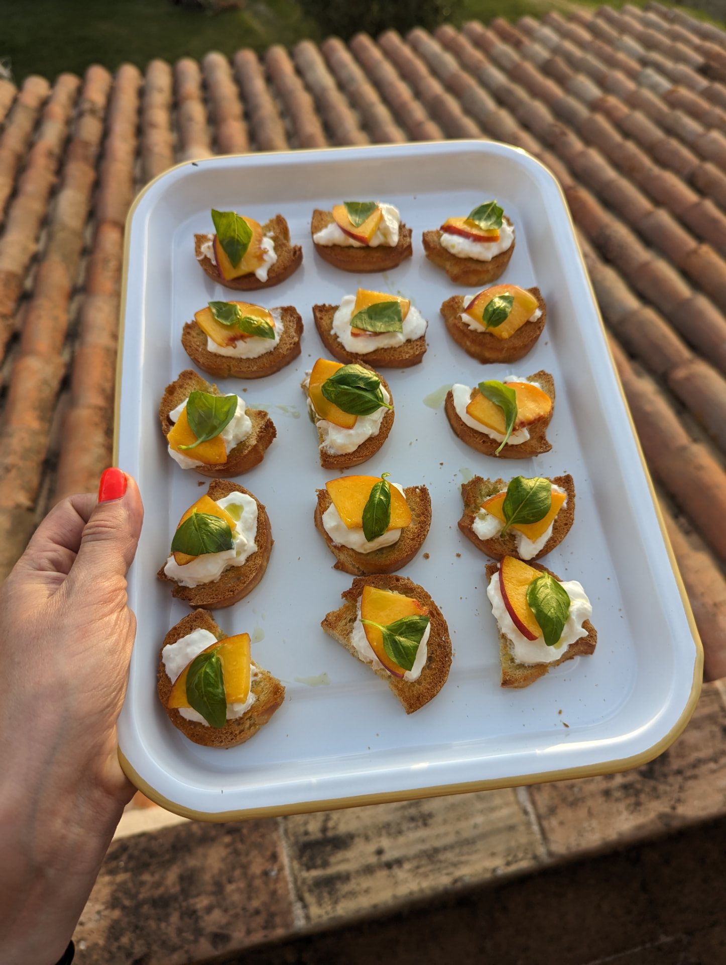 Peach, stracciatella and basil crostini arranged on a serving tray